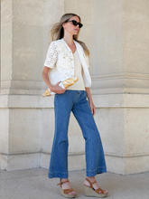 a lady wears a flared jeans with a white lace top